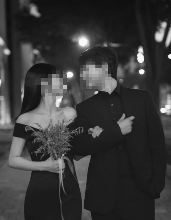 팔짱을 낀 커플의 흑백 사진. 얼굴 모자이크 처리.